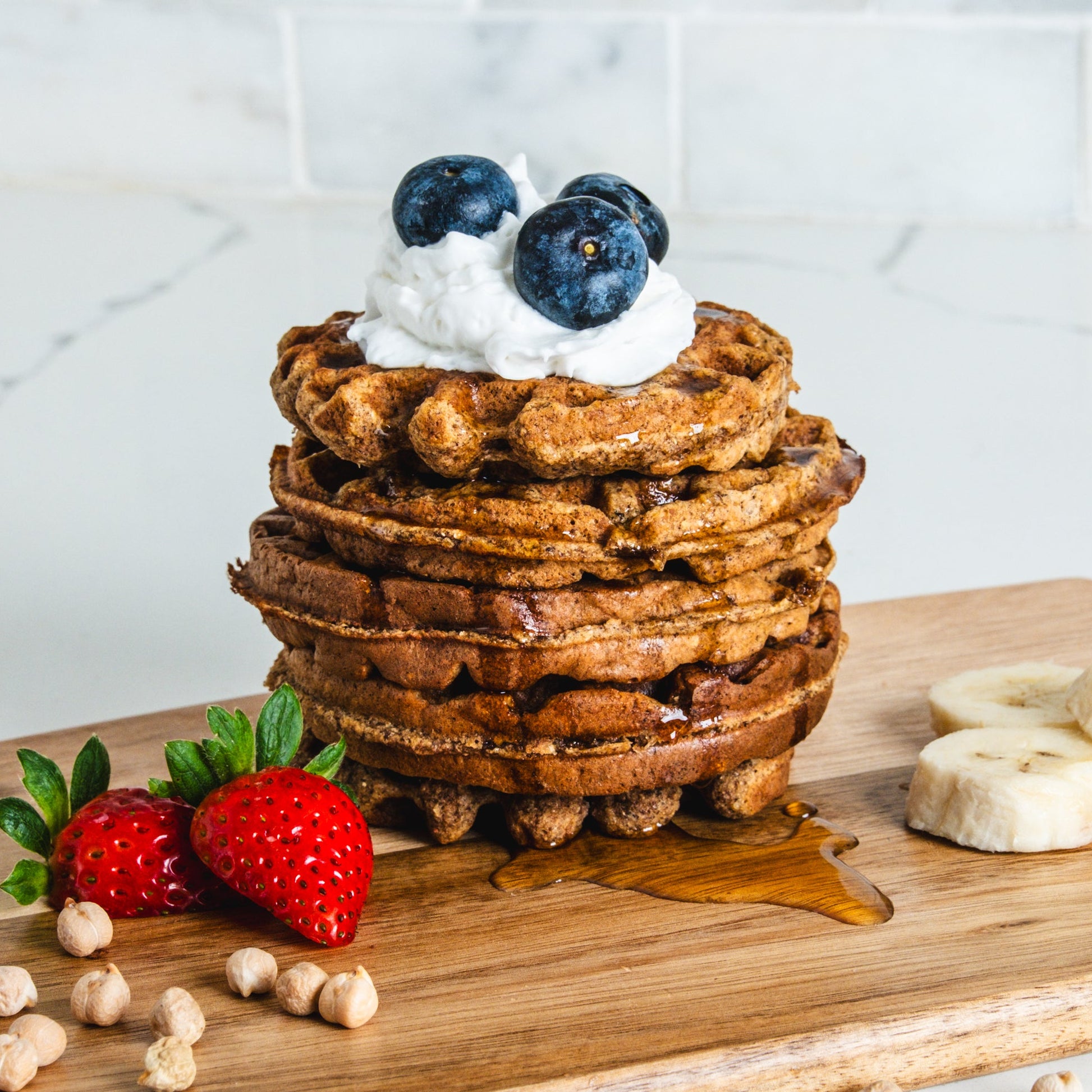 Waffles made with chickpeas topped with berries syrup and coconut whipped cream
