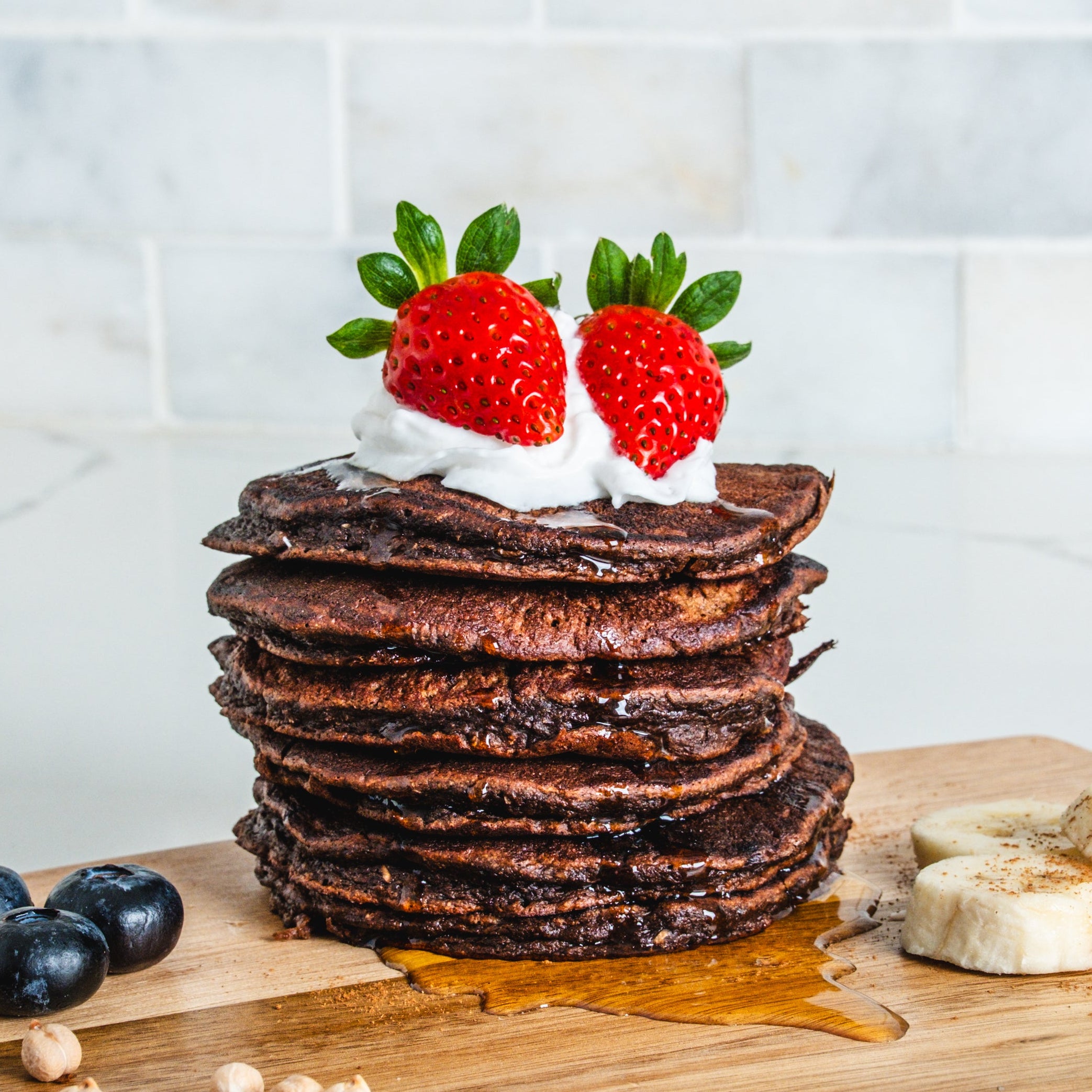 chocolate pancakes made with chickpeas and topped with berries, maple and whipped cream