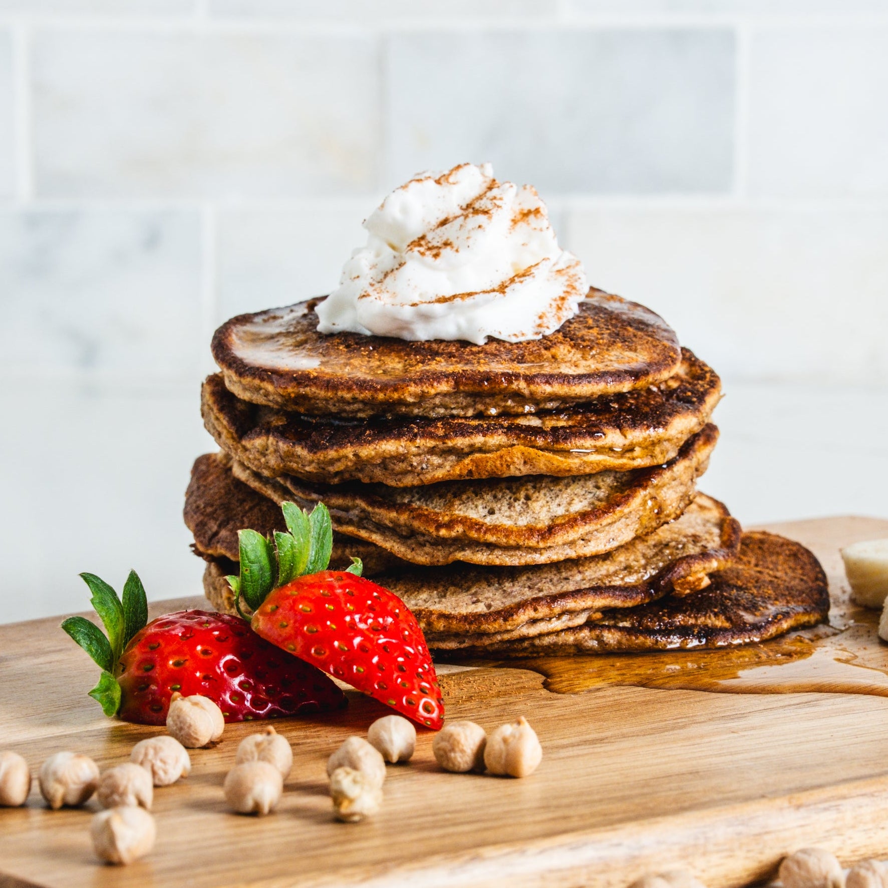 stack of pancakes with chickpeas and fruit and bananas and whipped cream 